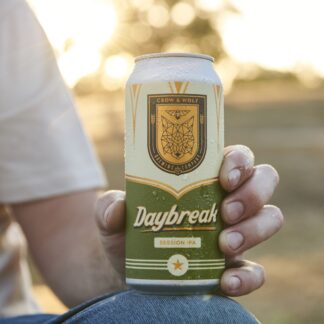 A hand holding a can of Daybreak Session IPA outdoors at golden hour